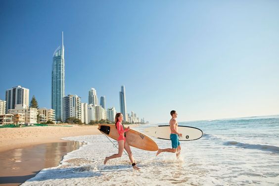 Couple carrying surfboards on their way to the beach in Broadbeach, Gold Coast.