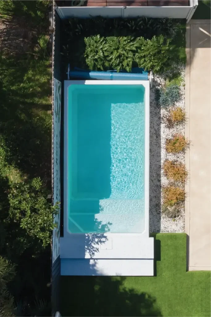 A serene backyard featuring a Plungie Original pool surrounded by lush greenery