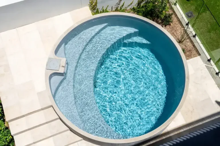 Luxurious round inground plunge pool with a built-in lounge area