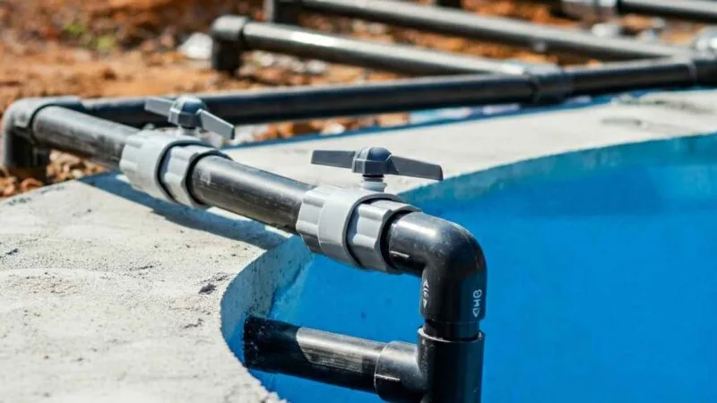 Close-up of PVC pipes being connected for water circulation and filtration, running along the edge.