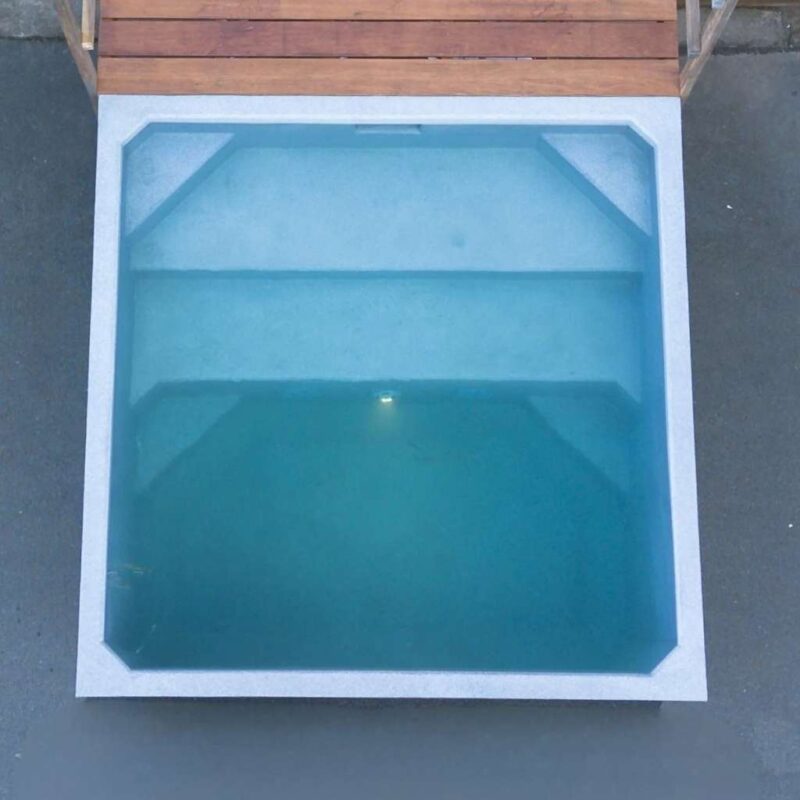 Plungie Quad, a compact 2.2m x 2.2m square precast concrete plunge pool filled with water, installed beside a timber deck.