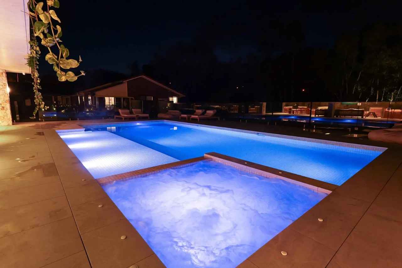 Luxury swimming pool with spa and LED lighting at night, showcasing modern design, premium finishes, and resort-style outdoor living on the Gold Coast.