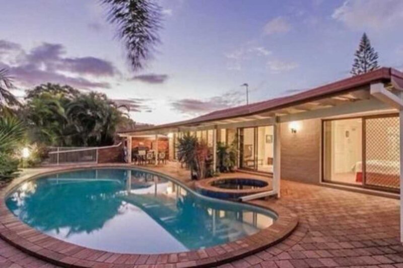 Residential backyard pool before renovation with outdated brick coping, faded concrete surface, and older design at a Gold Coast home.