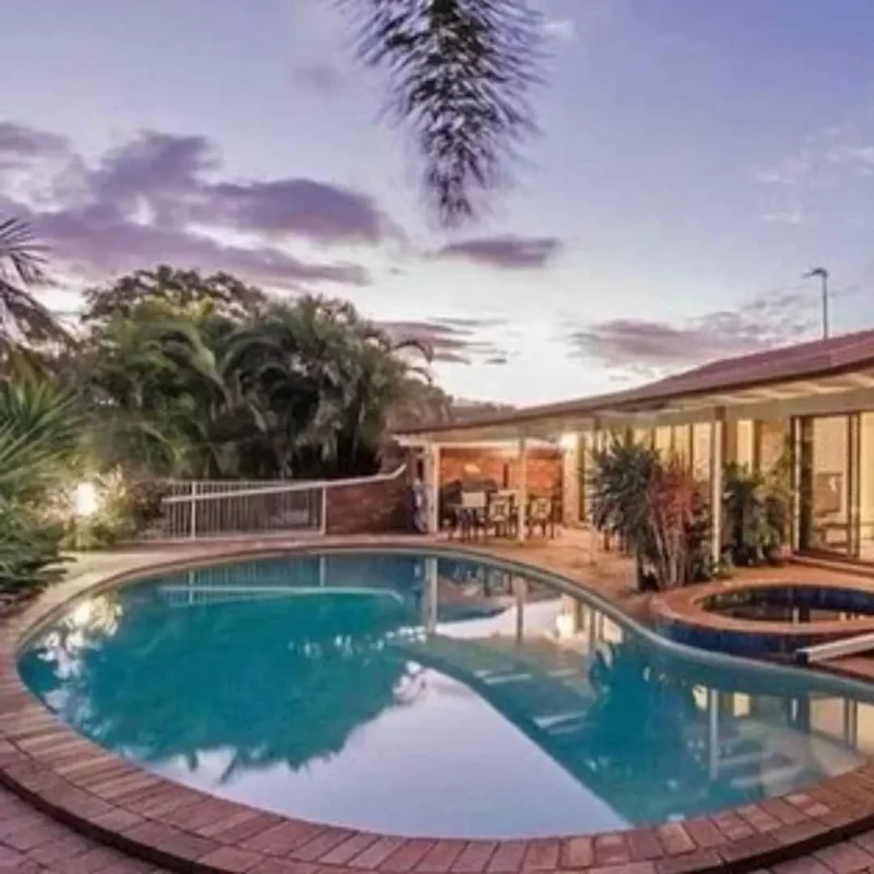 Renovated backyard swimming pool with curved design, spa area, and outdoor entertaining space in Palm Beach