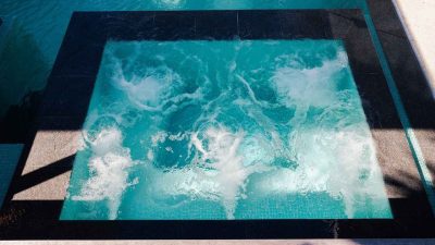 infinity-edge-pool Luxury infinity-edge swimming pool with integrated bubbling spa section, showcasing modern concrete design and crystal-clear turquoise water.